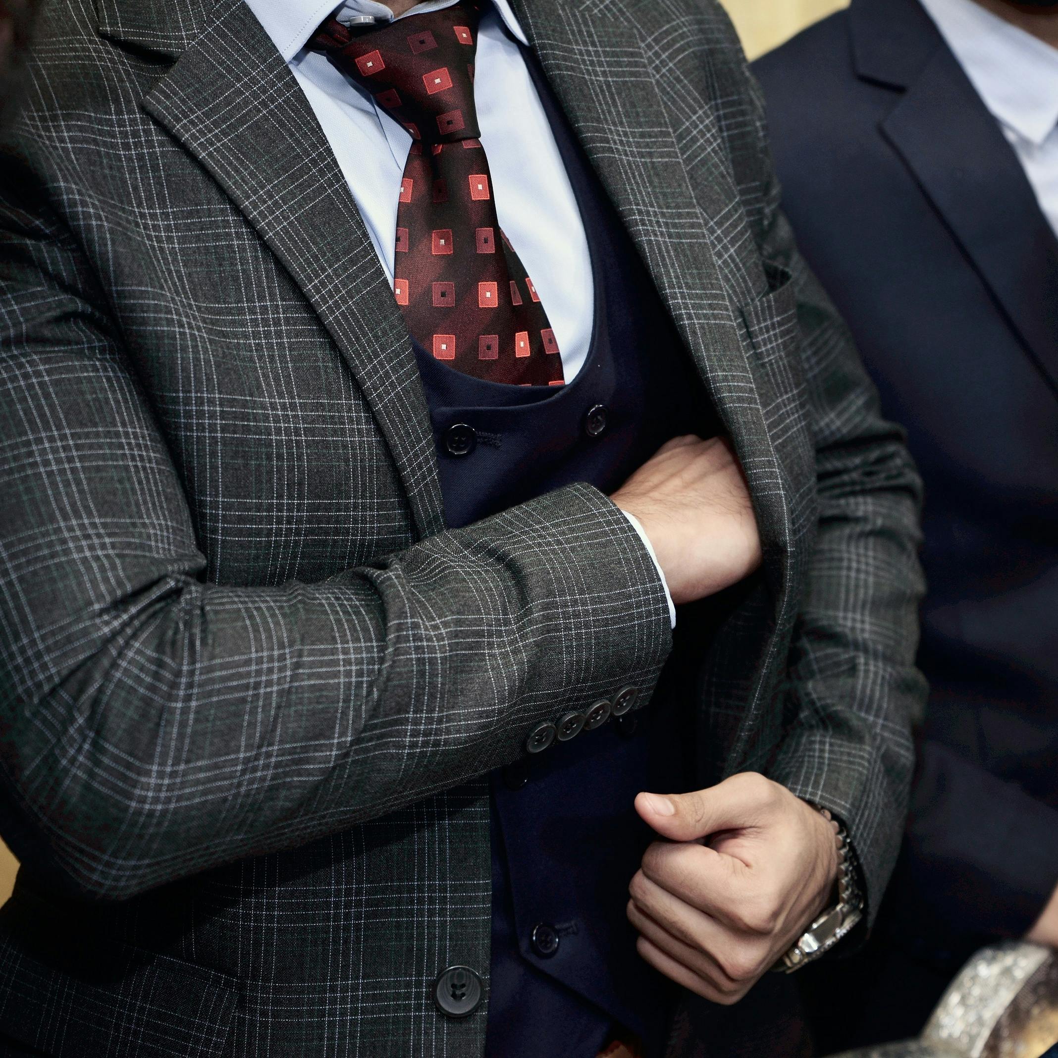 Close-up of a man in a designer suit, adjusting his tie, showcasing business fashion.